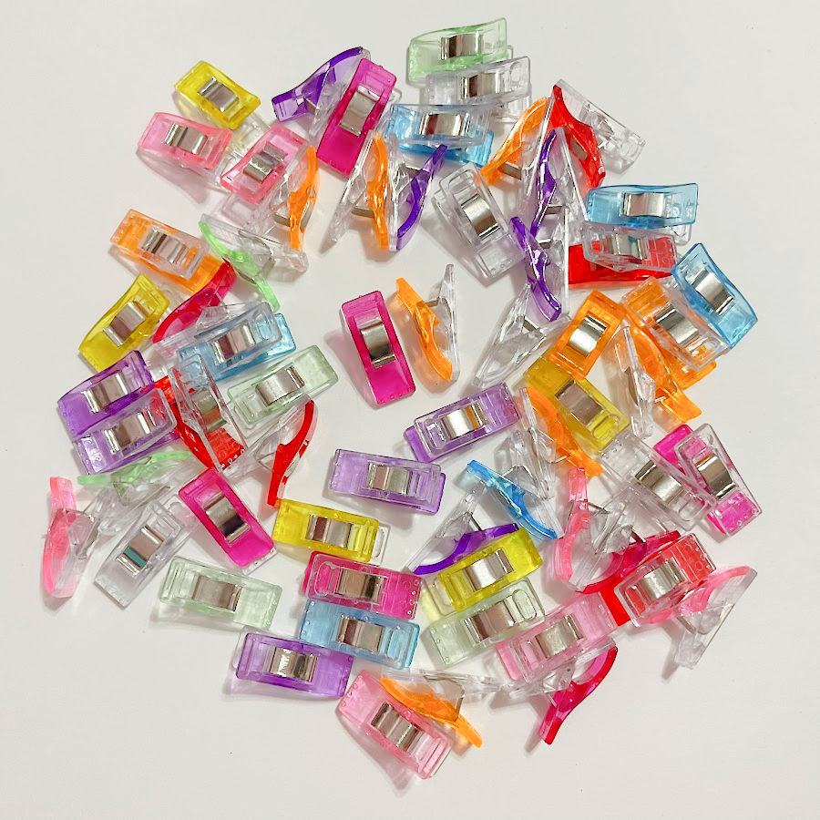 Image shows a collection of fabric clips which can be used to hold fabric instead of pins