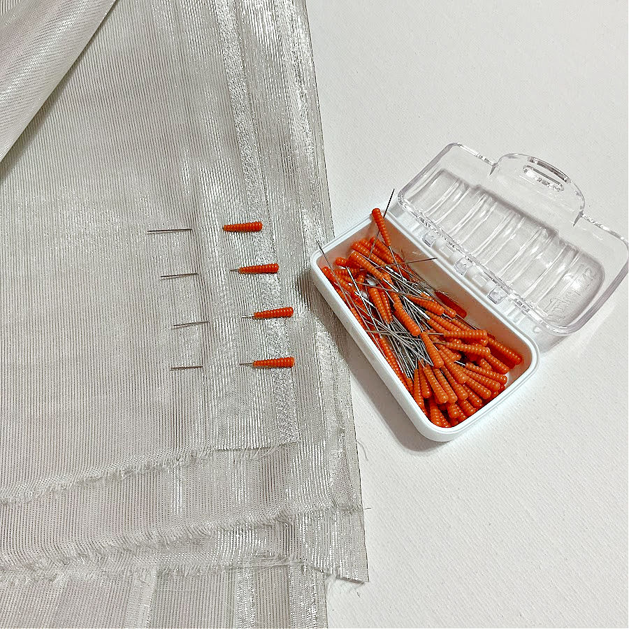 Image shows a box of magic pins heat resistant pins and four pins already inserted into a piece of fabric