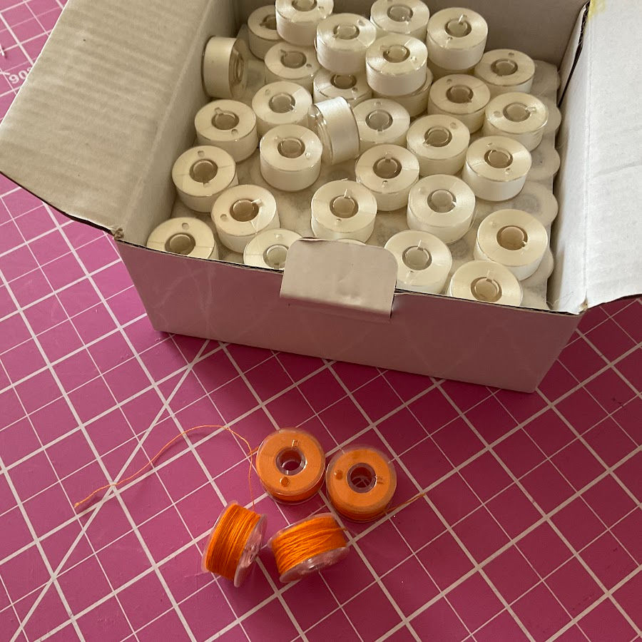 Prewound bobbins in a box and others loose on a cutting mat