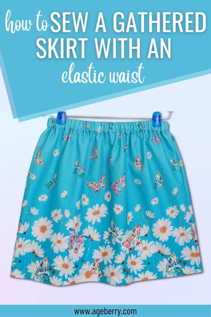 A bright blue gathered skirt with an elastic waist, decorated with a cheerful print of daisies and butterflies. The skirt is clipped to a hanger against a soft blue background. The text overlay reads, "How to Sew a Gathered Skirt with an Elastic Waist," with the website ageberry.com displayed at the bottom.