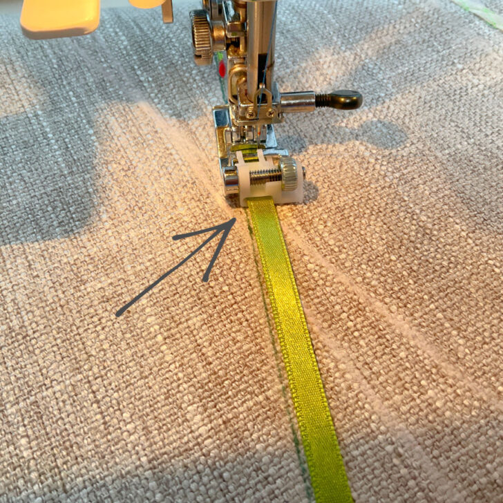 Image shows the correct positioning of the ribbon in the sequin ribbon presser foot and the correct way to align the foot with the stitch guide line