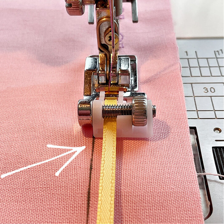 The image shows the correct positioning the sequin ribbon sewing foot in rapport to the desired stitch position. An arrow points to the correct position.