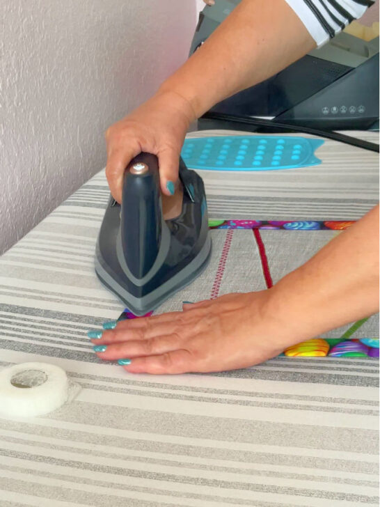 A woman ironing the Easter table runner to fix the hem tape before final stitching