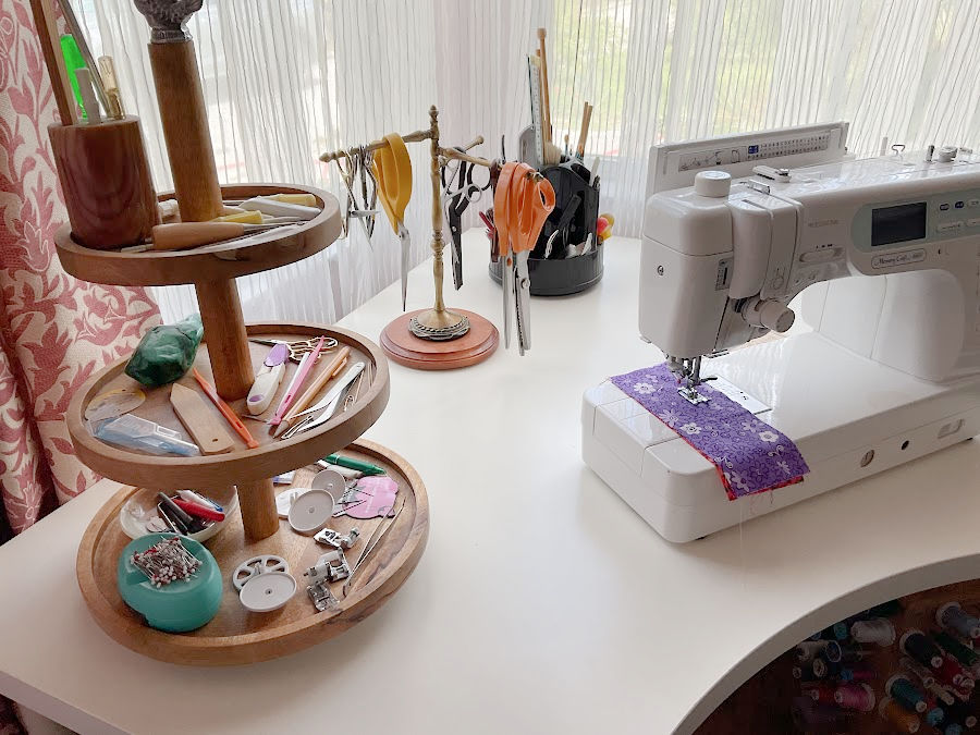 sewing table with 3-tier lazy susan with sewing tools on each shelf, a scissor storage tree and a sewing machine