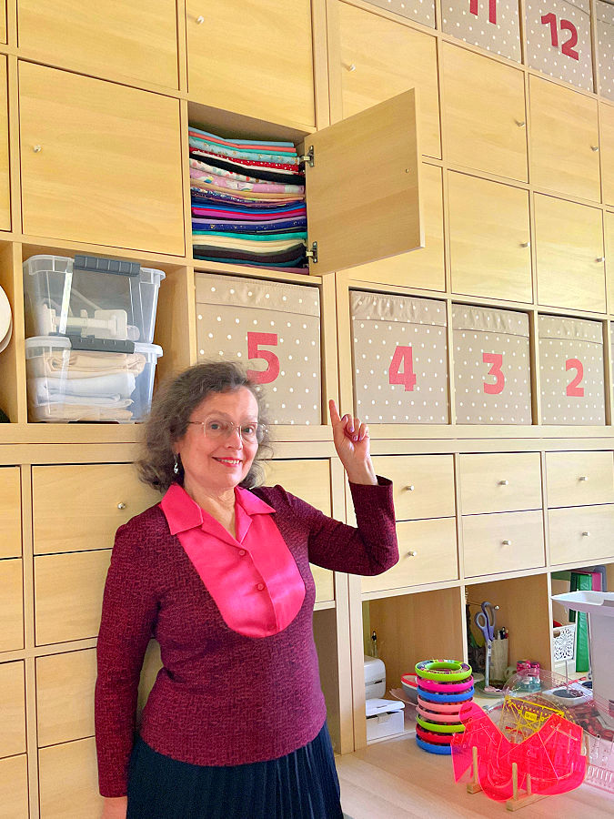 A woman standing in front of a custom made storage wall unit built from Ikea standard blocks