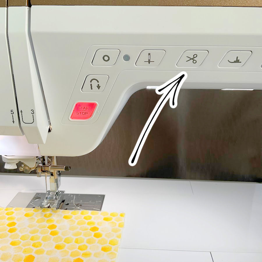 image shows the thread cutter button on a sewing machine