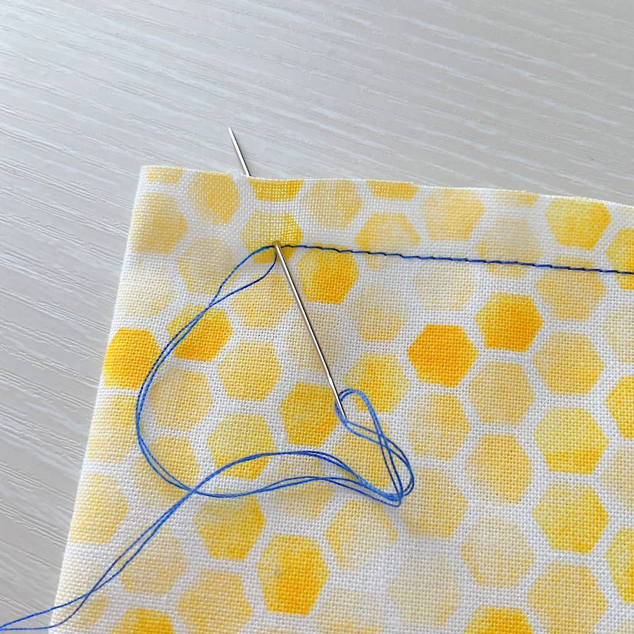 hiding the thread tails by hand between the two layers of fabric using a hand sewing needle