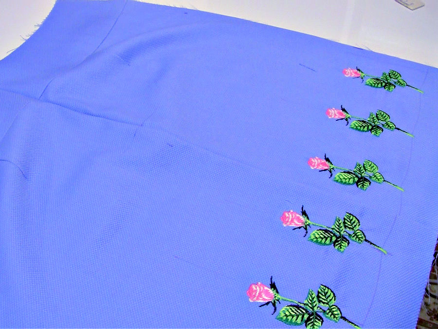 A piece of material for a skirt with embroidery having a pen cil mark on it as a result of ironing over a dissappearing pencil trace