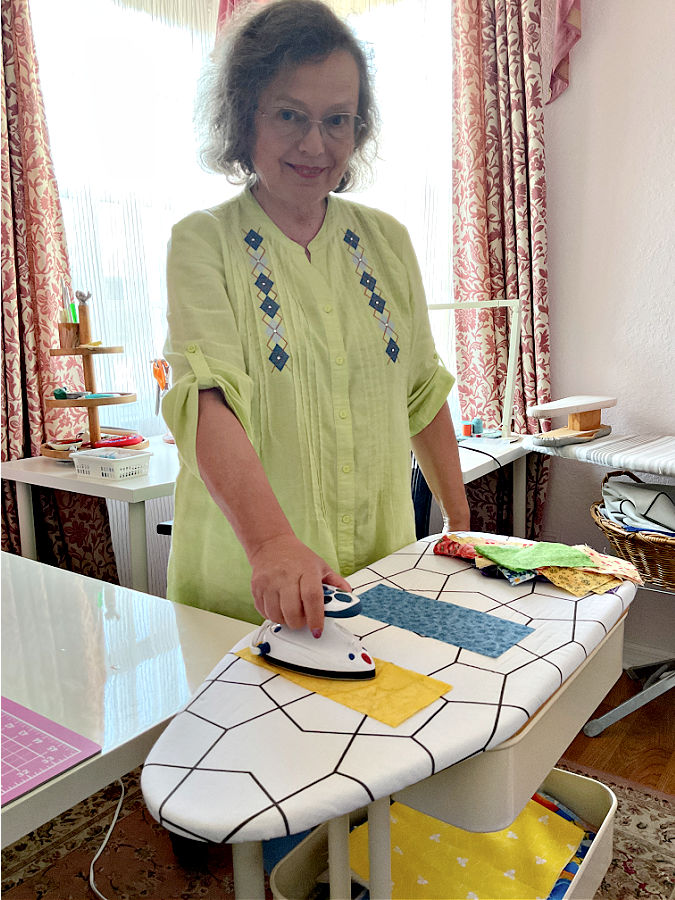 A woman using a mini iron on a mini ironing board