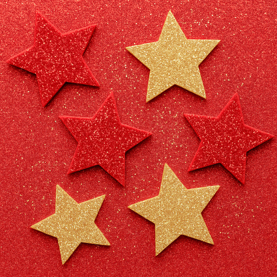 stars cut out from golden and glitter felt laying on a background of the red glitter felt material