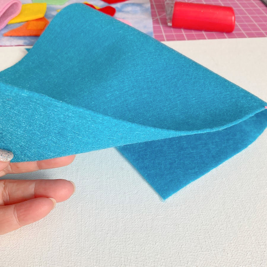 a woman's hand holding a piece of medium body felt light blue color