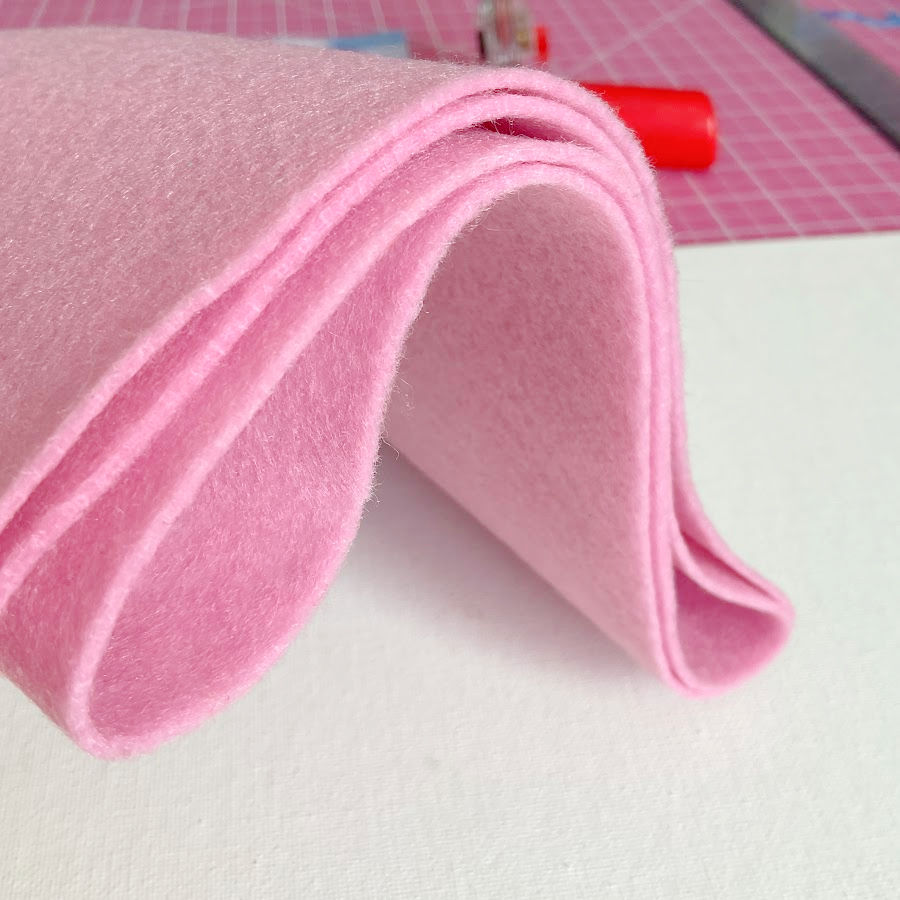 a piece of pink soft felt in the background a sewing table with a cutting mat