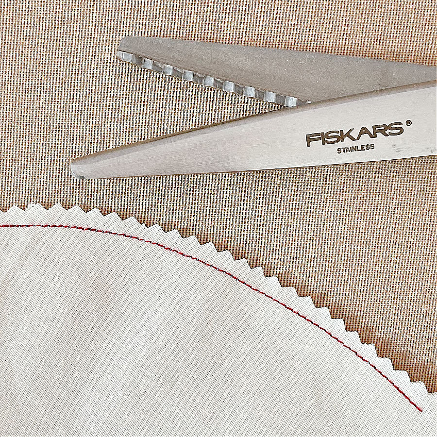 a pair of pinking shears being used to cut notches in a piece of material with an outside curve