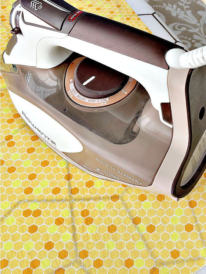 a rowenta steam iron sitting on a piece of fabric on the ironing board