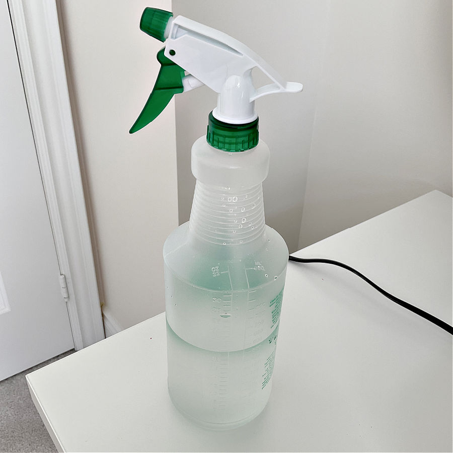 a spray bottle half filled with water sitting on a table