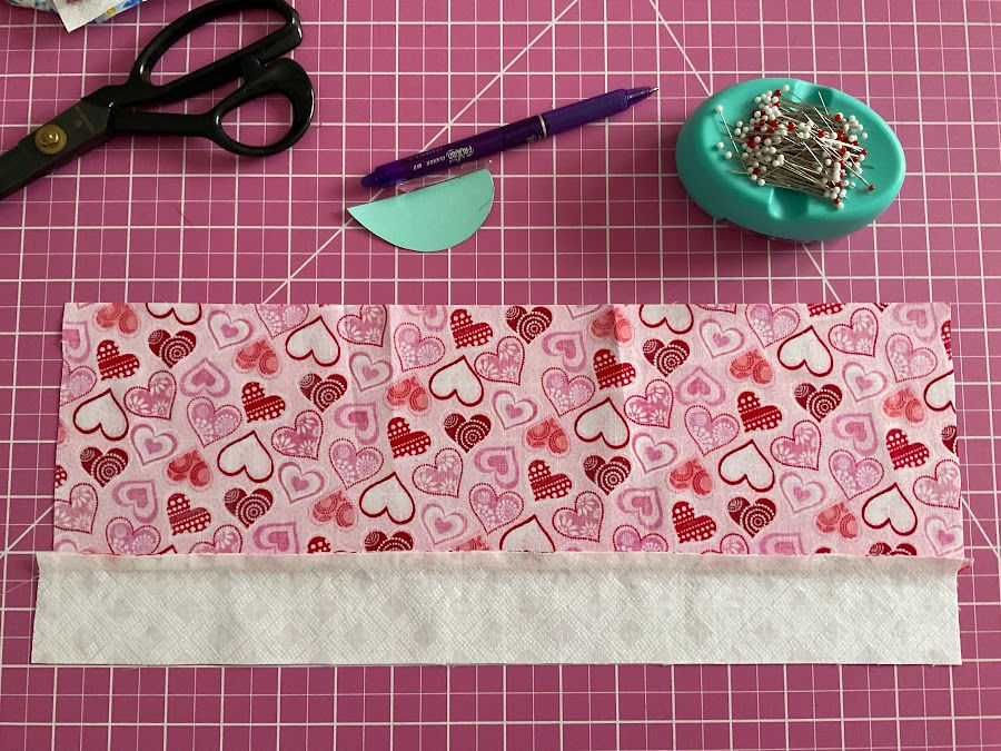the strip of colored fabric prepared for the angel ornament after the strip of white fabric was sewn on it, the seam was pressed and the seam allowance was also pressed