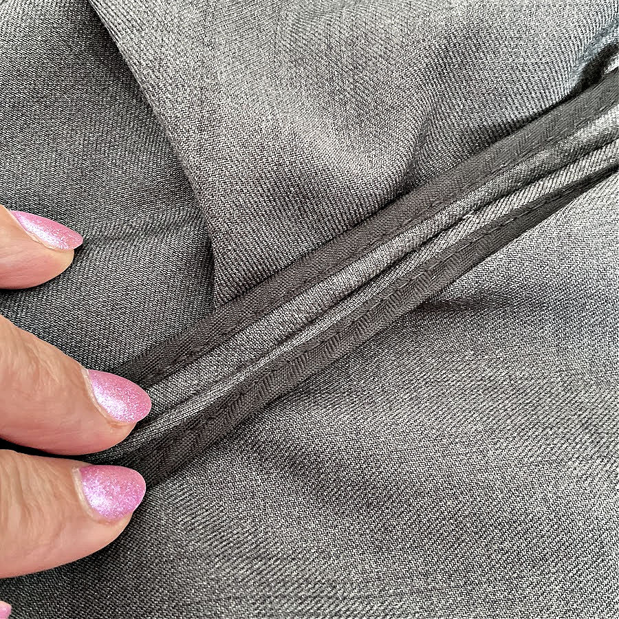 a womans hand showing a seam which uses binding for the seam allowance which is not visible on the outside