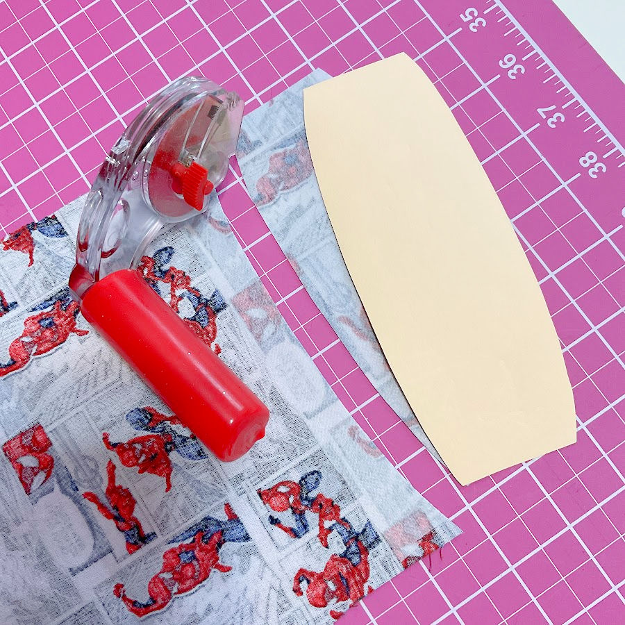 a rotary cutter after cutting a piece for the cord keeper sits on a piece of material on a cutting mat