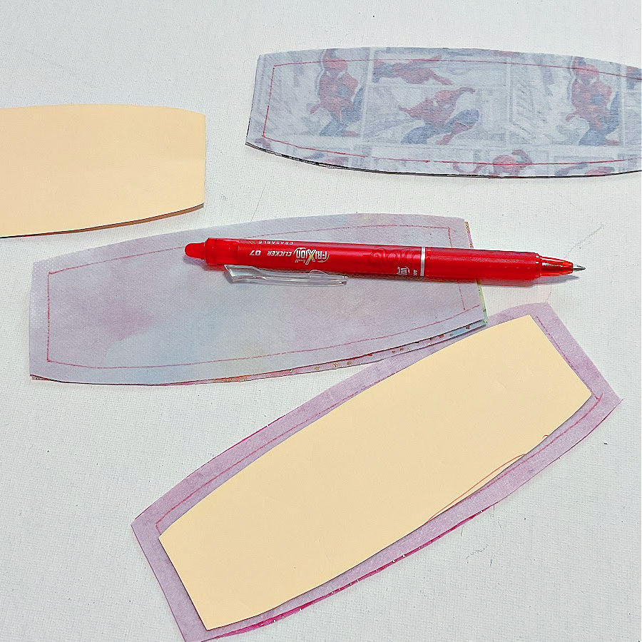a frixion marking pen sitting on some pieces of material cut for the cord keeper project with markings for seam allowances pieces of pattern are also visible