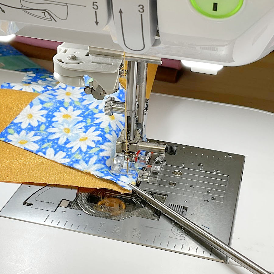 a pair of long and narrow tweezers holding the end of the fabric while sewing the end of the curved seam