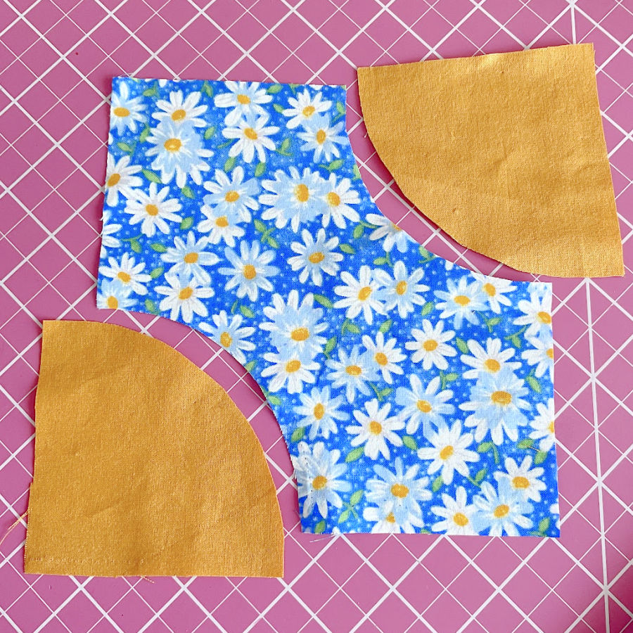 pieces of fabric quarter circles cut in preparation for sewing