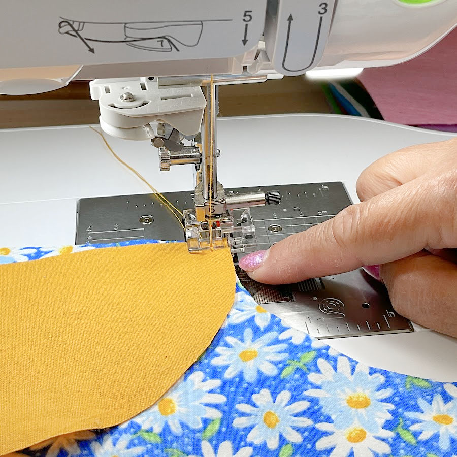 a womans hand pointing to the correct position of the presser foot after being lowered to start the seam