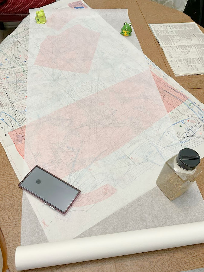 tracing paper over a pattern with various objects used as pattern weights ceramic frogs spice jar phone