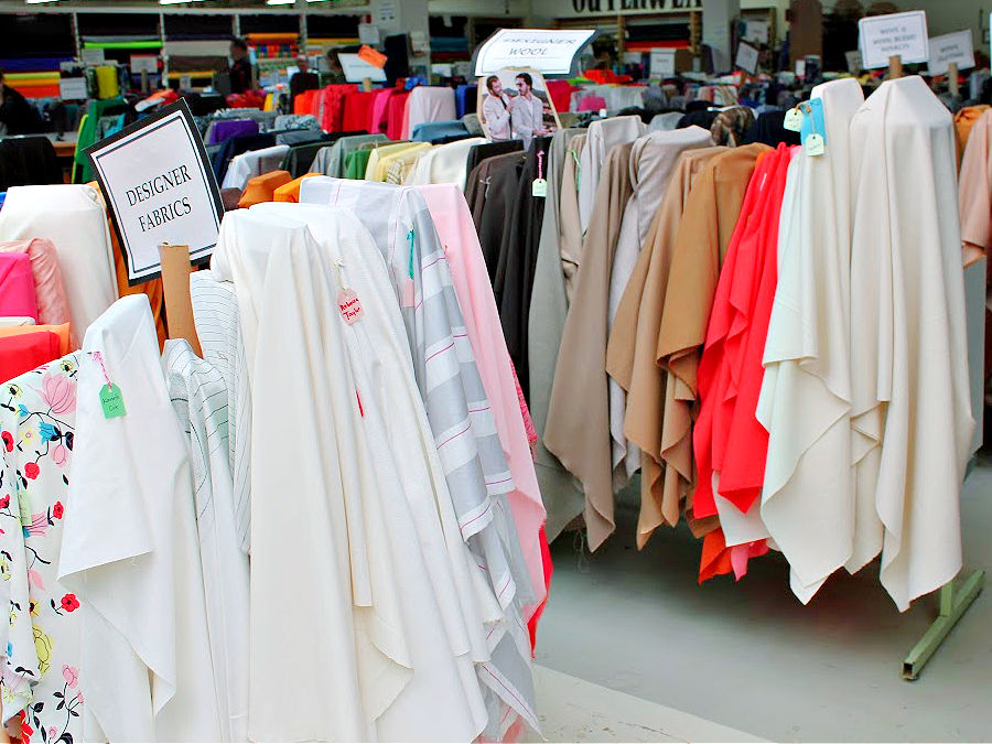 fabric bolts and pieces in a fabric store with a label in the foreground reading "designer fabrics"