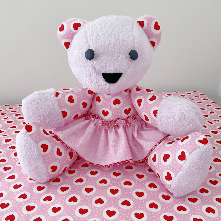 finished memory bear with skirt sitting on a piece of fabric