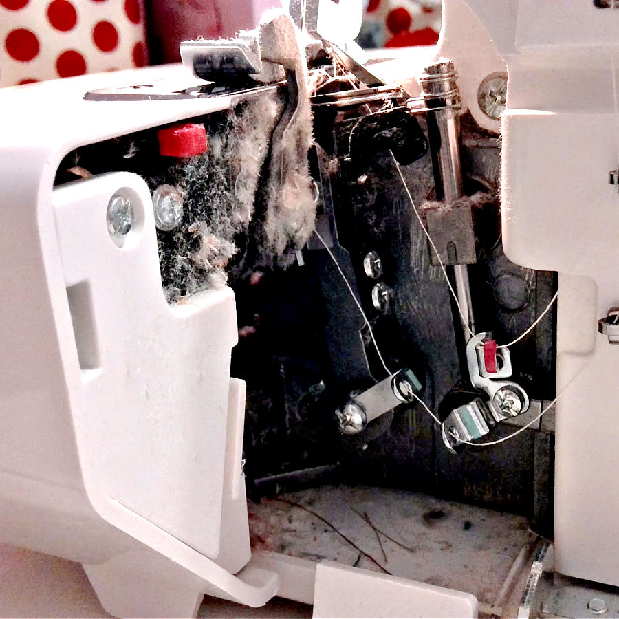 the inside of a serger overlock machine showing considerable dust and lint accumulation
