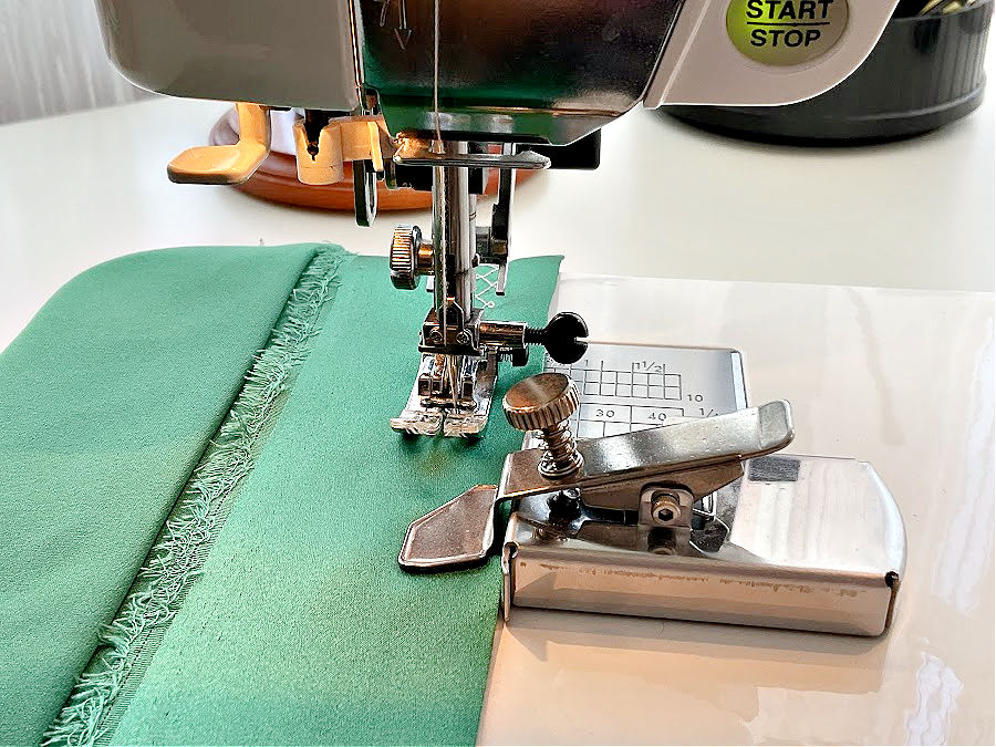 magnetic seam guide in the foreground installed on a sewing machine with the needle assembly in the background