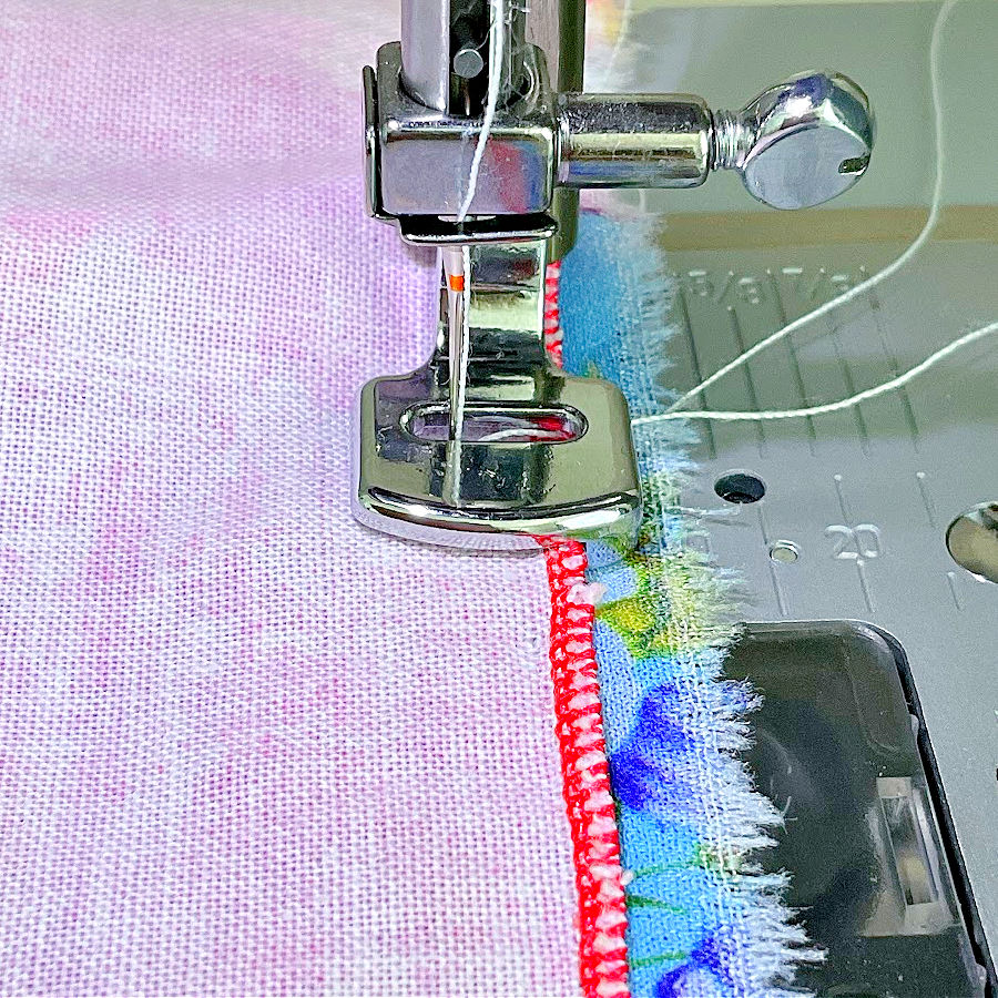 the sewing machine needle assembly with the gathering foot attached while in use on two pieces of material