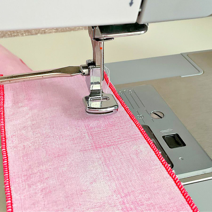 gathering foot for low shank sewing machine attached to a singer sewing machine a piece of pink material under the foot