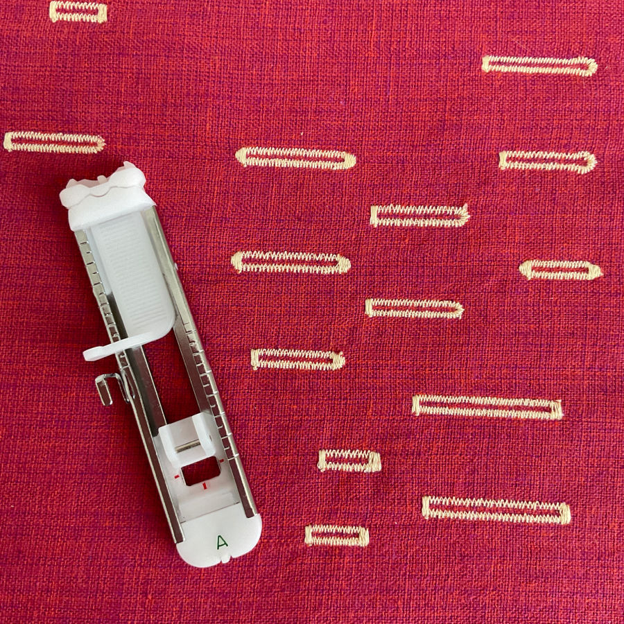 one step buttonhole foot with cording slots on a piece of fabric with many buttonholes sewn as example