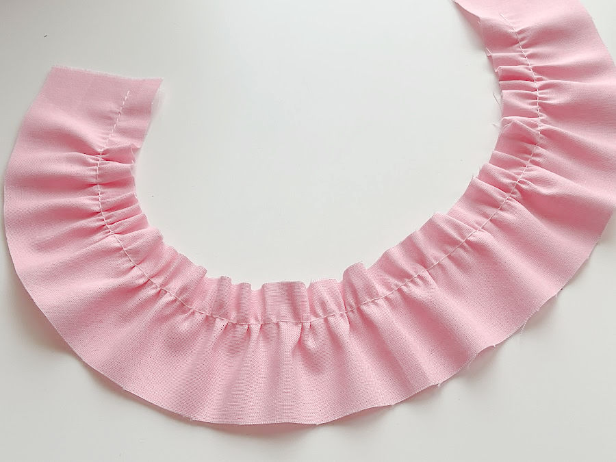 a piece of pink material sewn on the janome machine with the gathering foot attached showing very good quality gathers