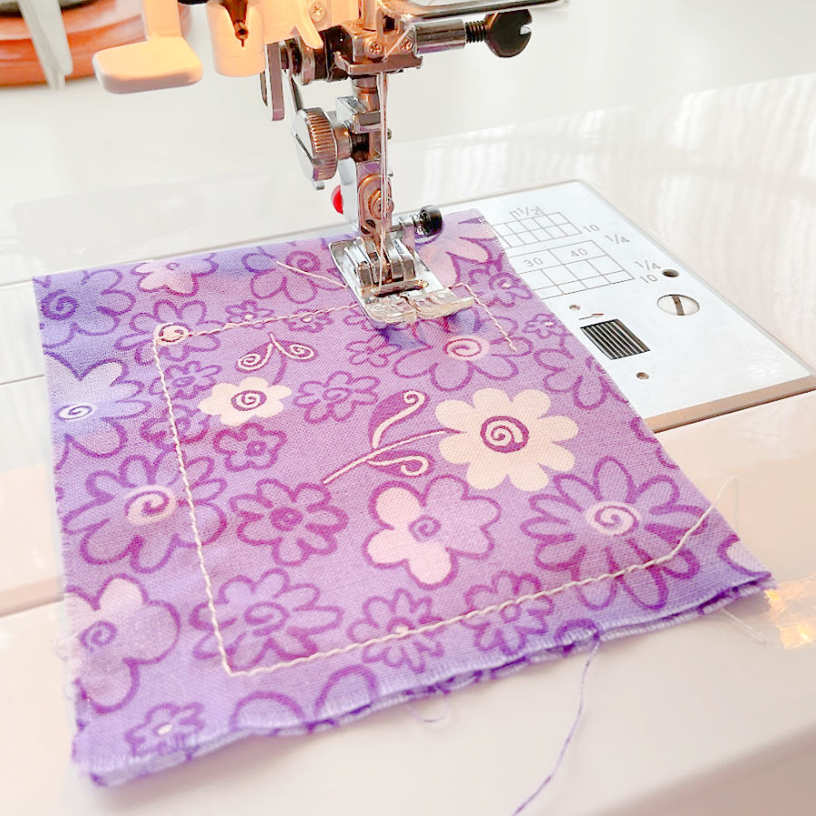 a sewing machine needle assembly while sewing a seam on a piece of pink scrap fabric for test