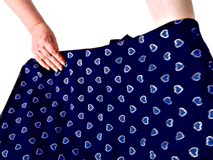 a womans hand showing a piece of dark blue fabric with printed hearts