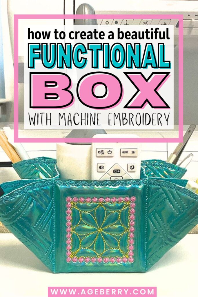 Turquoise fabric box with machine embroidery, featuring quilted sides and a decorative front panel stitched with yellow and pink floral motifs. The box is filled with household items including a white remote control and tools, sitting on a sewing table.