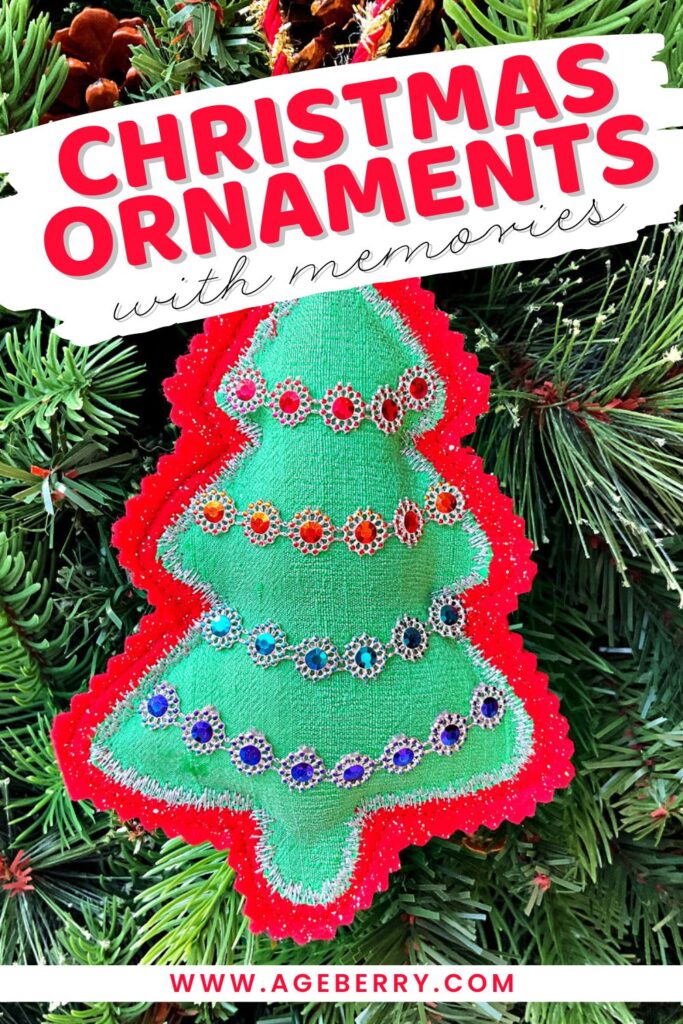 Handmade Christmas tree ornament sewn from green and red fabric, decorated with rows of colorful rhinestones resembling garlands. The ornament hangs on a pine tree branch.