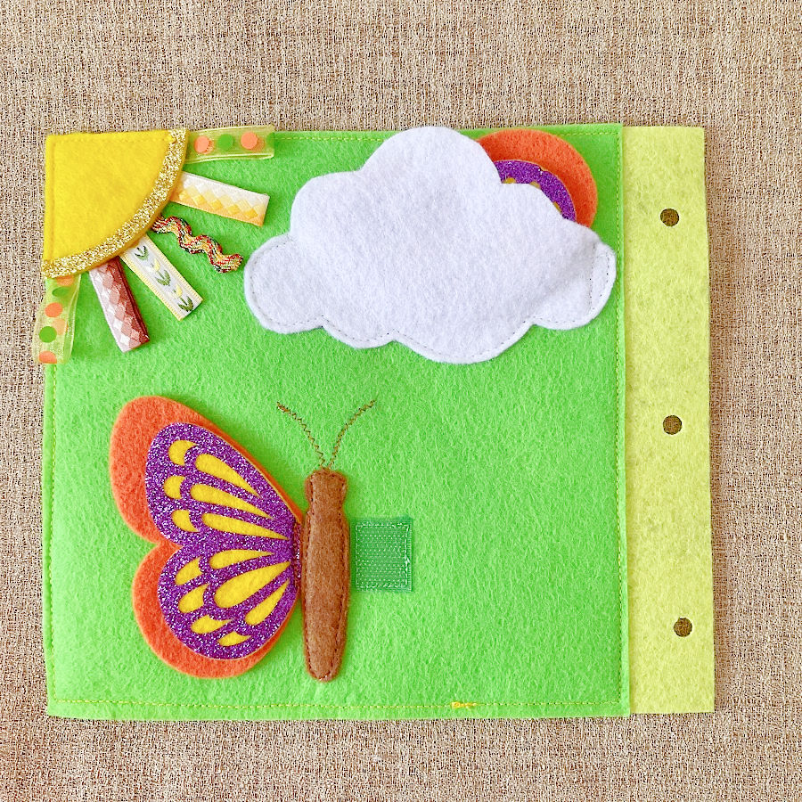 Butterfly on a page of the quiet book with one wing partially hidden in a pocket made out to look like a cloud