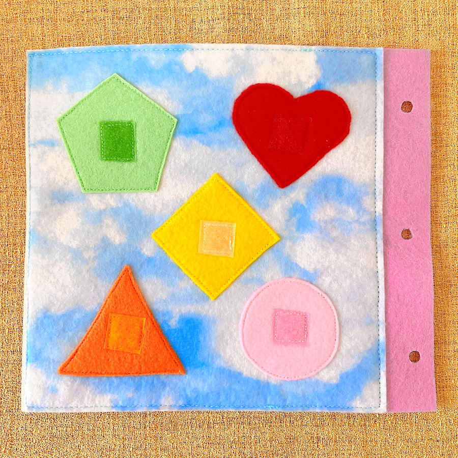 a page of the quiet book with various geometric shapes circle heart triangle square pentagon