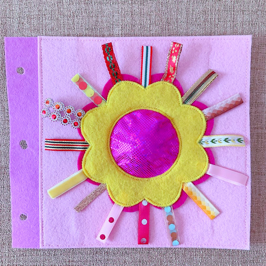 A bright red-and-yellow flower has ribbons for petals and a squeaky sound piece hidden beneath a central dome