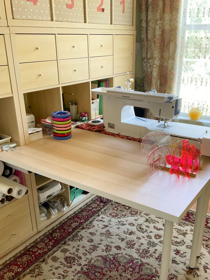 a sewing machine on a table a storage unit made with Ikea Kallax units with various notions and sewing tools