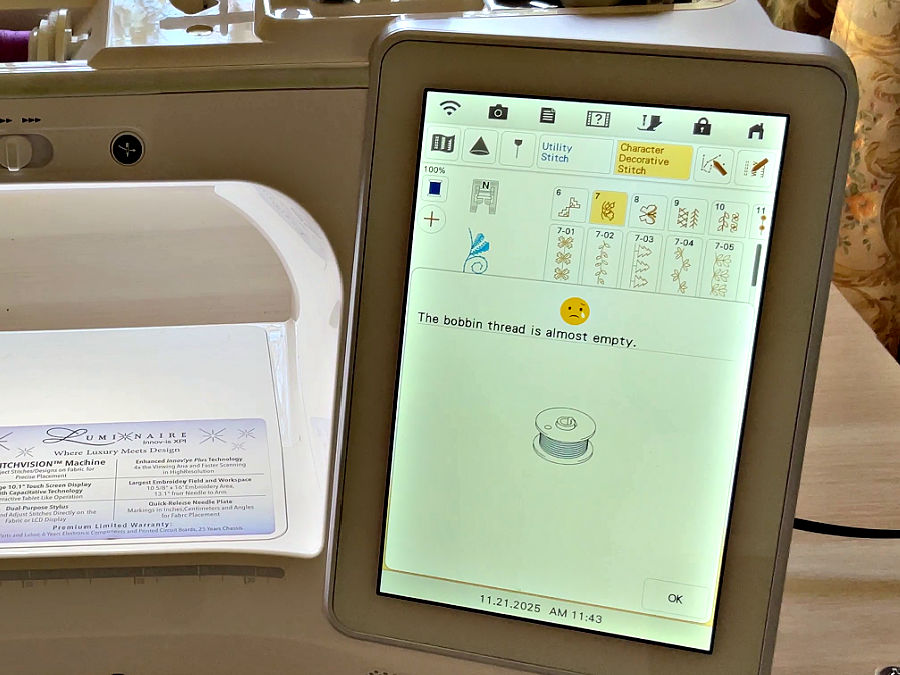 the brother luminaire shows a warning message "bobbin thread is almost empty" with an emohi with a tear