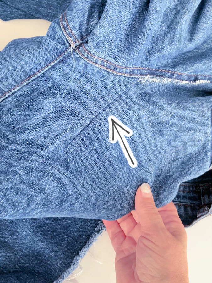 the jeans on the right side with an arrow pointing to the area of the rip after sewing by machi8ne the stitch is almost invisible