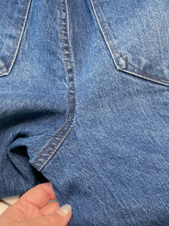 a womans hand shows the repaired rip which now is almost invisible