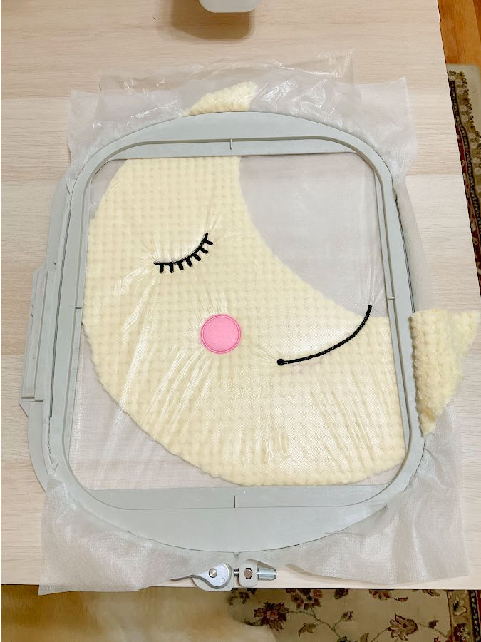 the moon plushie in the hoop after embroidery of the eye, cheek and mouth