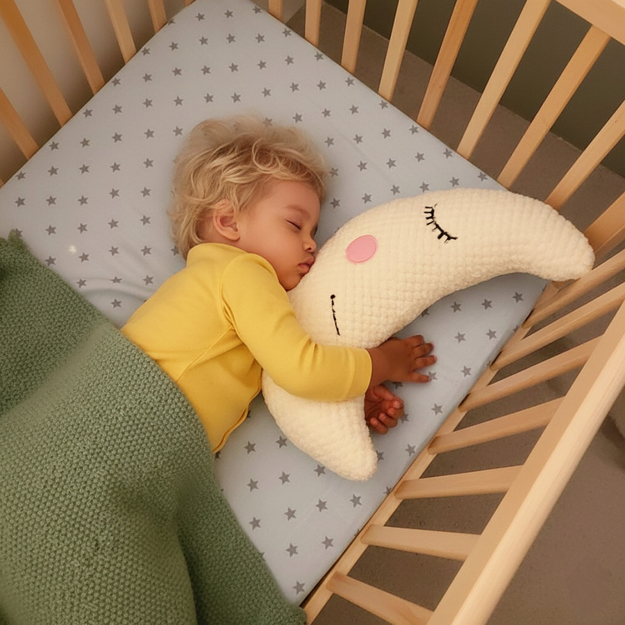 a blond toddler hugging the moon plushie while sleeping