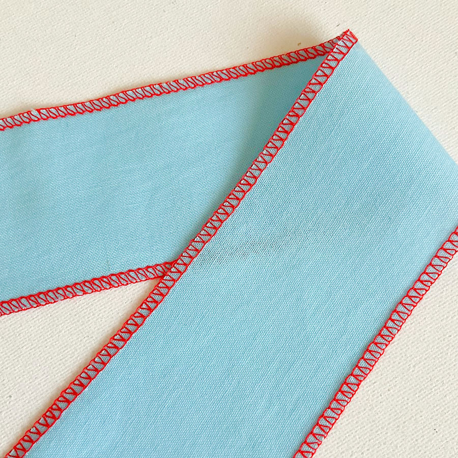 a folded piece of material showing both the upper and under sides of a three thread serger overlock stitch