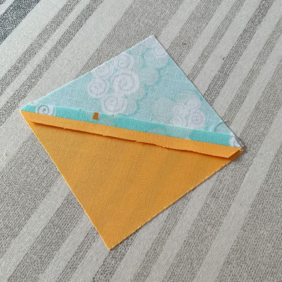 a half square triangle after pressing with an iron press the seam looks better but still not perfect